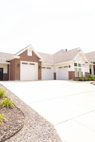 Exterior featuring brick and siding finishes, multiple garage doors, and a concrete driveway