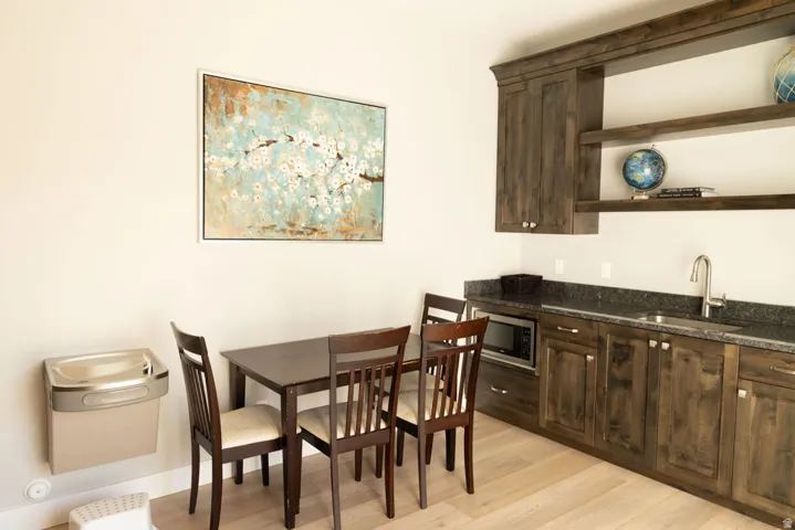 Built-in wet bar featuring dark wood-finish cabinetry, a stainless steel sink with a gooseneck faucet, and integrated microwave