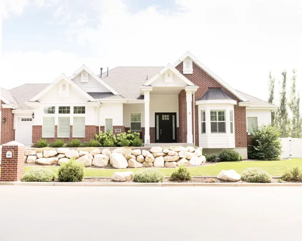 Brick and siding exterior with a covered porch, bay window, and a stone retaining wall