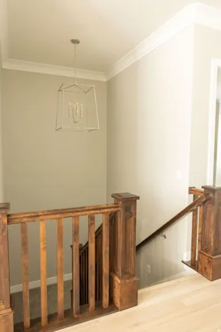 Wood-finish flooring, dark wood railings, and a modern geometric pendant light fixture