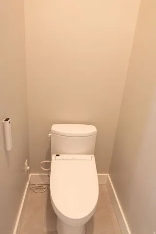 White toilet with bidet attachment and tile flooring