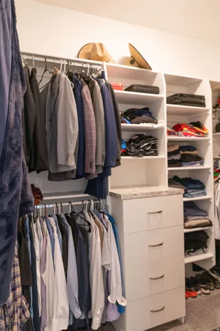 Custom closet system featuring hanging rods, built-in shelving, and drawers with a stone-finish countertop