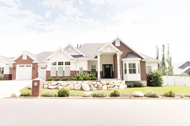 Brick and siding exterior with a covered porch entry, bay window, attached two-car garage, and established landscaping