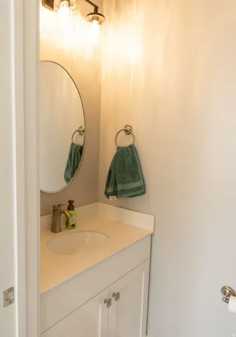 Vanity with white shaker cabinetry, an undermount sink, a countertop with an integrated backsplash, and a brushed nickel faucet