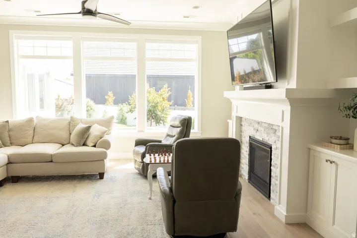 Wood-finish flooring, white trim, a built-in fireplace with a stone surround, and multiple windows