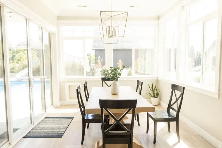 Light wood-finish flooring, expansive windows, multiple sliding glass doors, and a geometric chandelier
