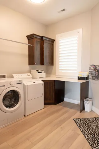 Light wood-finish flooring, built-in dark wood cabinetry, white plantation shutters, and a corner desk surface
