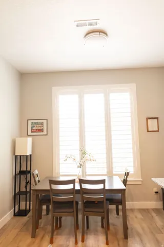 Wood-finish flooring with a white trim, featuring a window with white plantation shutters