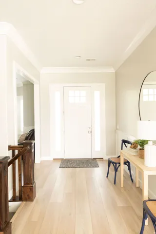 Entryway featuring wood-finish flooring, a white paneled front door with sidelights, and crown molding