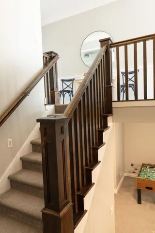 Carpeted staircase with dark wood-finish newel posts and railings