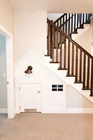 Staircase featuring dark wood newel posts and handrail, white risers, and a built-in under-stair structure with a door and window