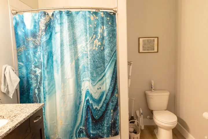 White shower surround, light wood-finish flooring, and a white toilet