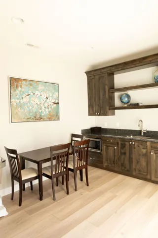 Wood-finish flooring, recessed lighting, built-in cabinetry, dark countertop, and an integrated sink