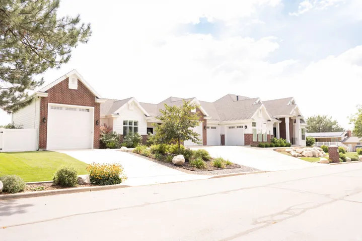 Brick and siding exterior with multiple garage bays, concrete driveways, and landscaped rock gardens