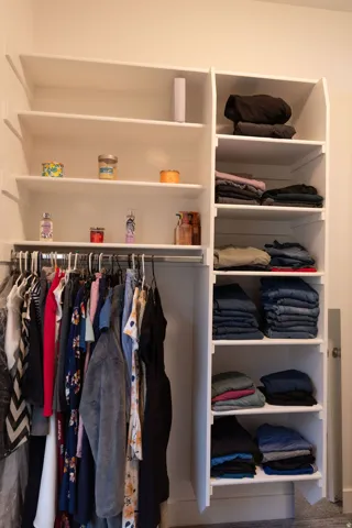 Built-in white storage system featuring multiple shelves and a hanging rod