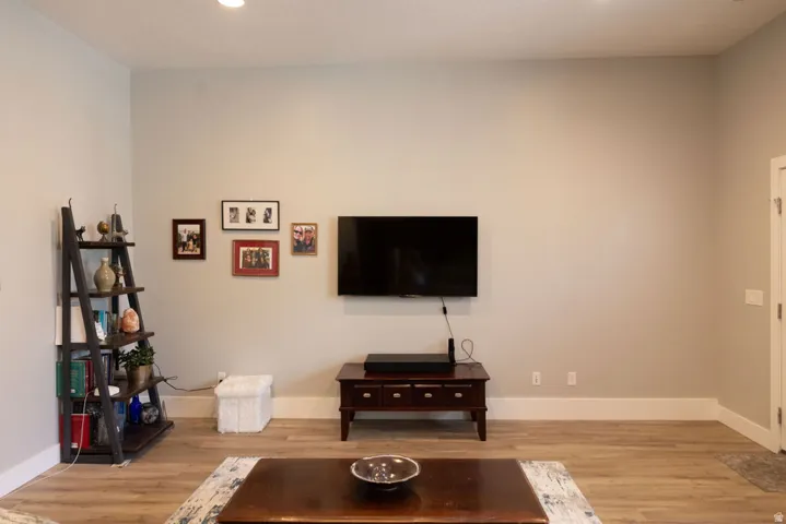 Recessed lighting illuminates the open living space featuring wood-finish flooring and light-toned walls