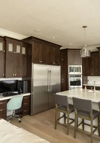 Stainless steel refrigerator, built-in stainless steel appliances, wood-finish flooring, dark wood-finish cabinetry, and a central island with countertop seating