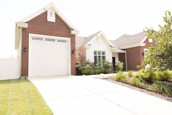 Brick and siding exterior with a pitched roof and a white garage door