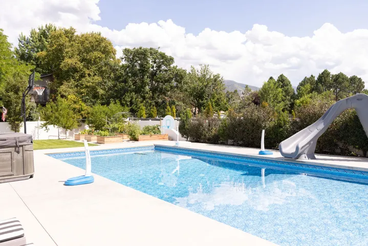 Expansive backyard featuring an in-ground swimming pool, concrete patio, spa, and raised garden beds