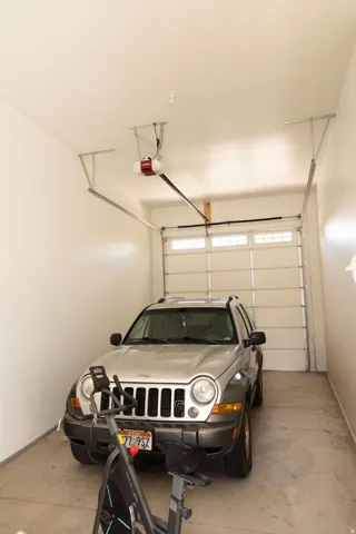 Attached garage with an automatic door opener, concrete flooring, and white walls