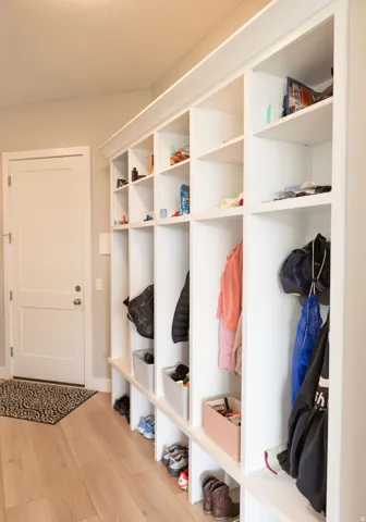 Built-in white storage cabinetry with individual compartments, wood-finish flooring, and a white interior door
