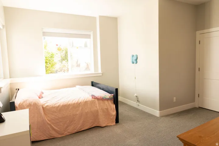 Light-filled room featuring a large window, neutral wall paint, and gray carpet flooring