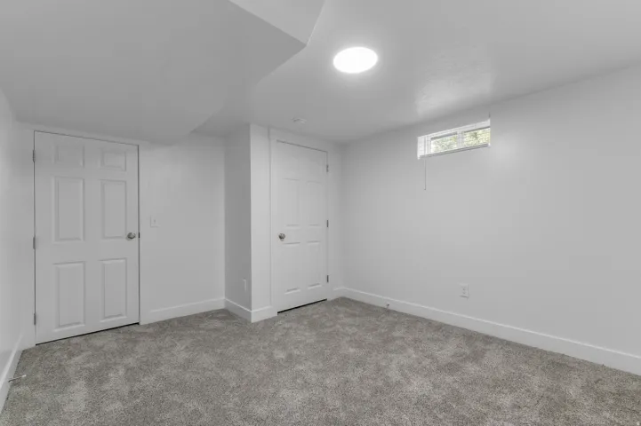 Recessed lighting, window with blinds, two paneled doors, and grey carpet flooring