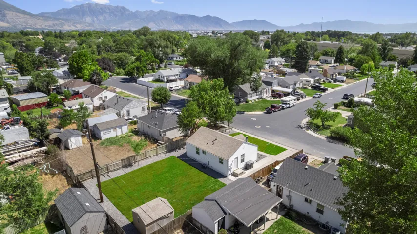 Expansive lot featuring a large grassy area, a perimeter fence, and mountain scenery
