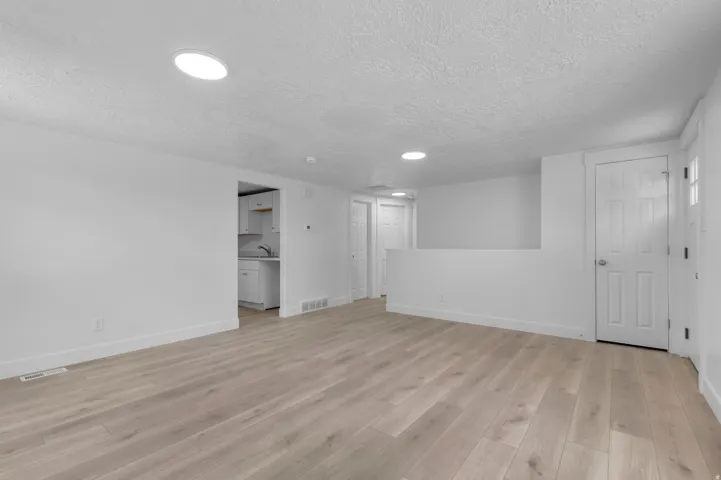 Light wood-finish flooring, recessed lighting, white panel doors, and a bright white color palette