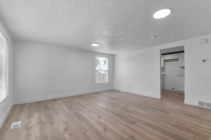Spacious room featuring light wood-finish flooring, white painted walls, and recessed ceiling lighting
