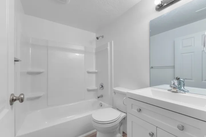 White vanity with integrated sink, chrome faucet, and mirrored medicine cabinet