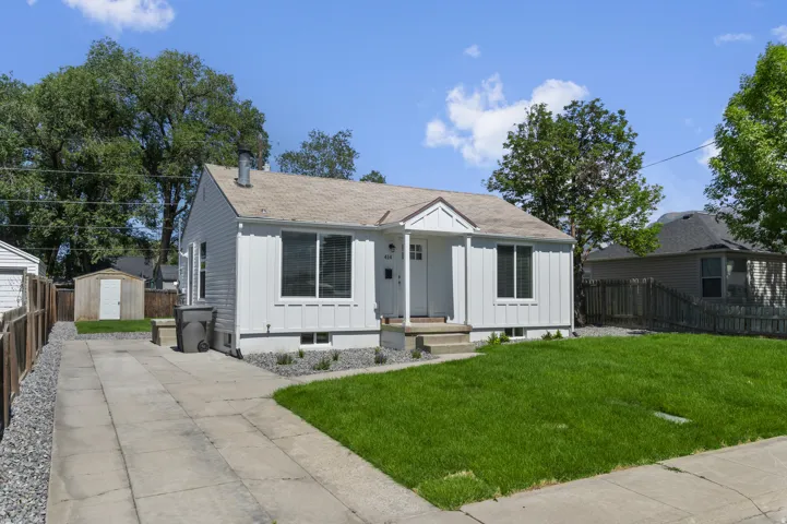 White siding exterior with a pitched roof, concrete driveway, and a front lawn