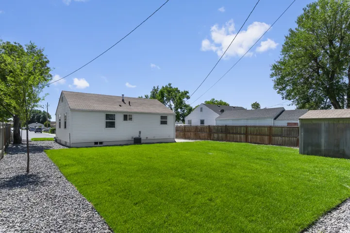 Expansive backyard featuring a manicured lawn, a gravel pathway, and a privacy fence