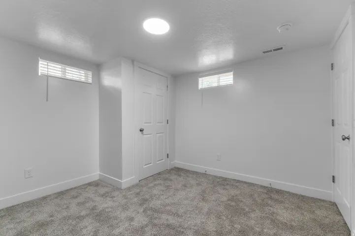 Plush carpet flooring, white walls, and a circular ceiling light fixture