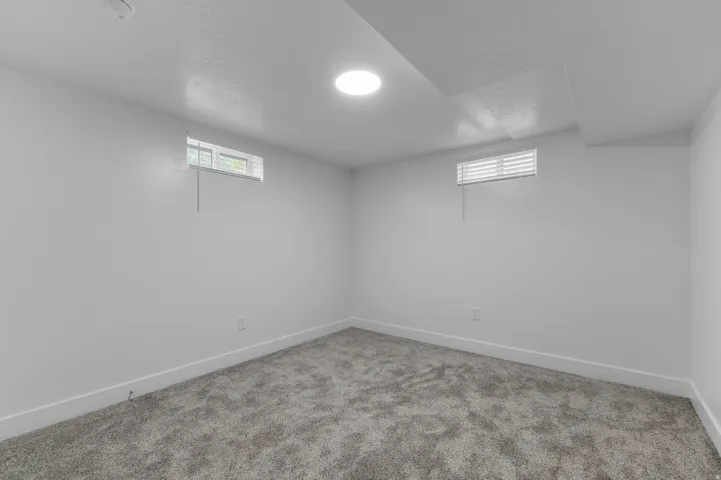 Light gray carpeting, two transom windows with white blinds, and a circular ceiling light fixture
