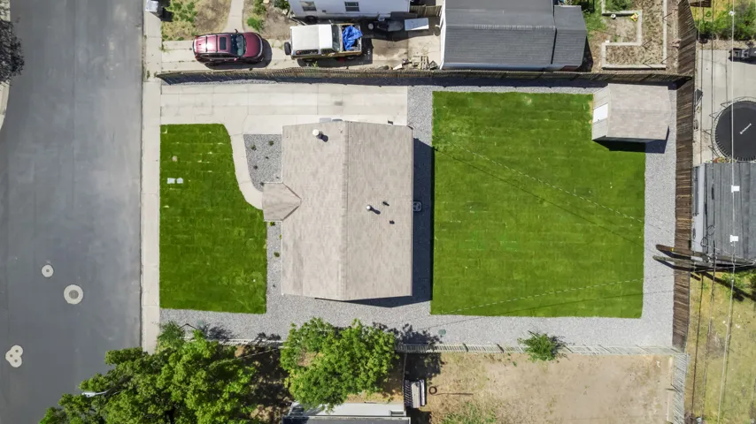 Expansive lot featuring a large grassy lawn, gravel landscaping, and a detached shed