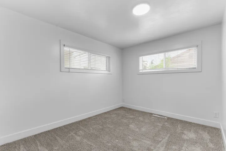 Neutral tone wall finish, plush carpeting, and two windows with blinds