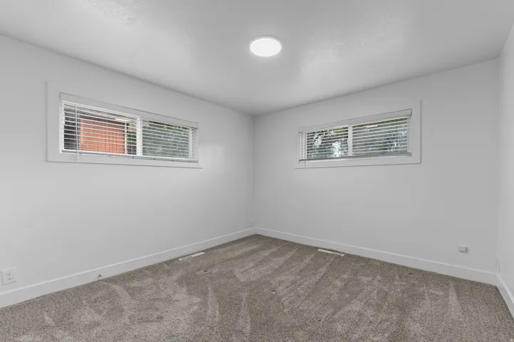 Plush gray carpeting, white walls, and two horizontal windows with blinds