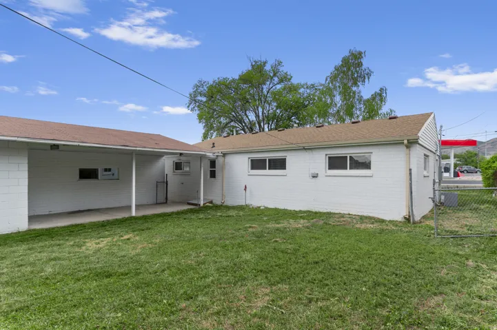 Expansive green space with an attached covered patio, white brick exterior, and multiple windows
