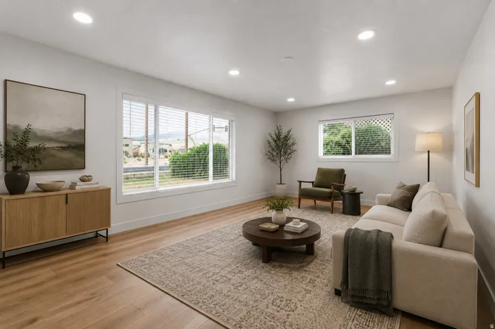Virtually staged. Recessed lighting illuminates this bright living area featuring wood-finish flooring and large windows with horizontal blinds