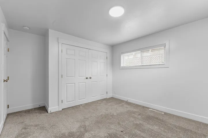 Neutral-toned wall-to-wall carpeting, white interior doors, and a horizontal window with blinds