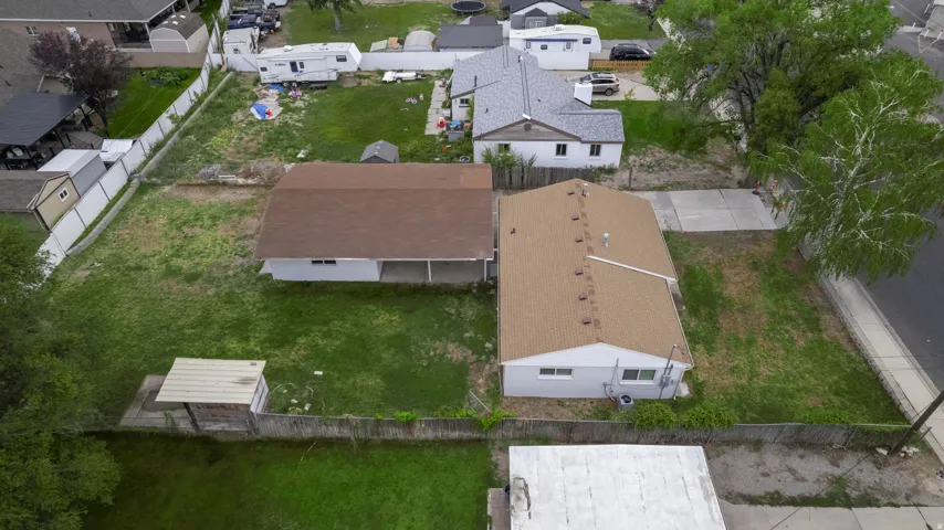 Expansive lot featuring two single-story structures, perimeter fencing, and a concrete driveway