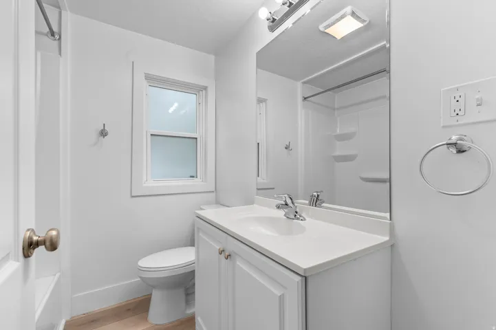 White vanity with an integrated sink, polished chrome faucet, and a large wall-mounted mirror