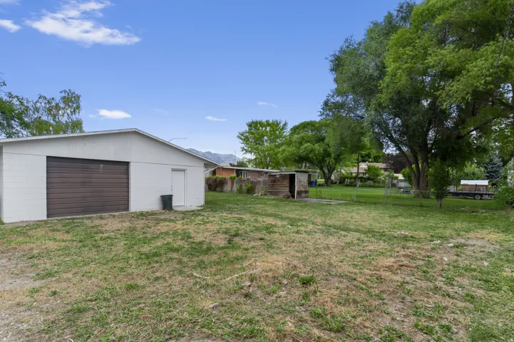 Detached garage with a roll-up door and separate entry door, accompanied by an additional utility shed