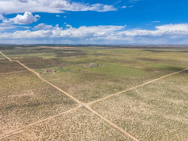 Expansive arid landscape featuring scattered vegetation and distant structures
