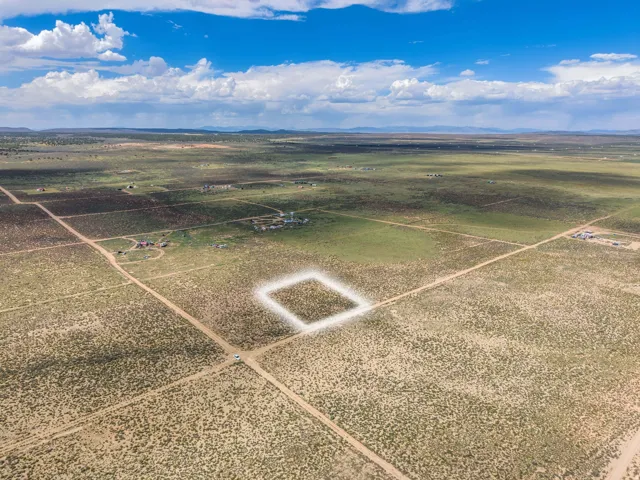 Expansive rural land with a discernible property outline, surrounded by open terrain and distant mountain ranges
