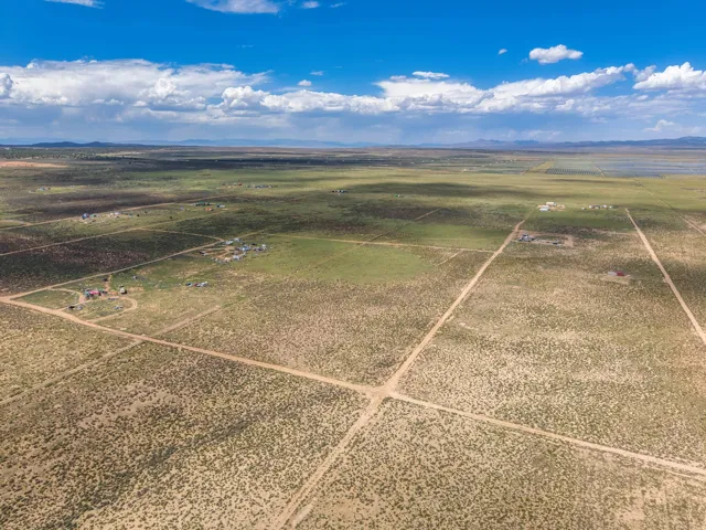 Expansive undeveloped terrain with visible dirt roads, sparse vegetation, and distant mountain ranges
