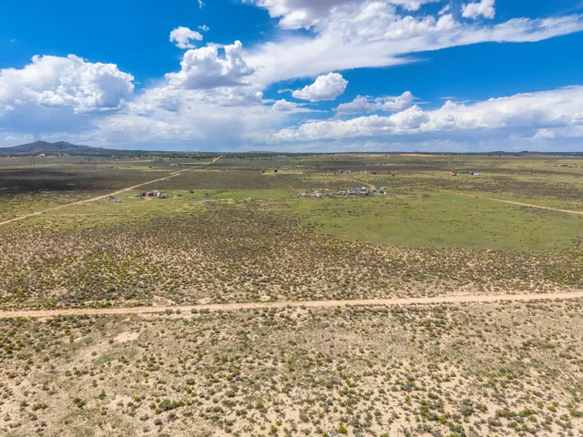 Expansive rural landscape featuring a dirt road and distant buildings