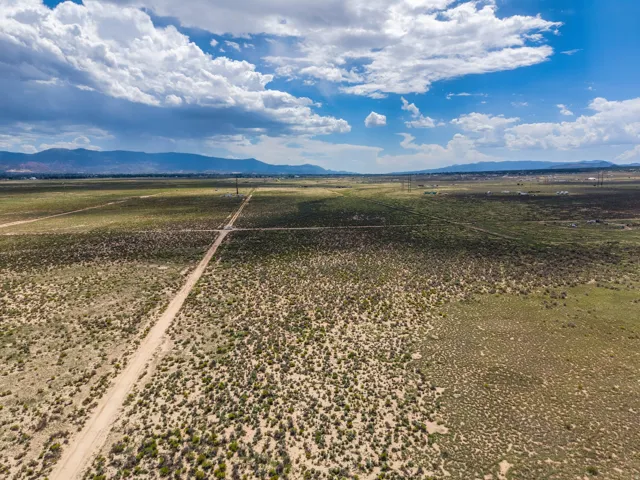 Expansive undeveloped land featuring a dirt road and distant mountainous terrain