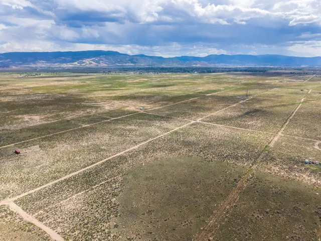 Expansive open land with distant mountain ranges, natural vegetation, and visible property divisions